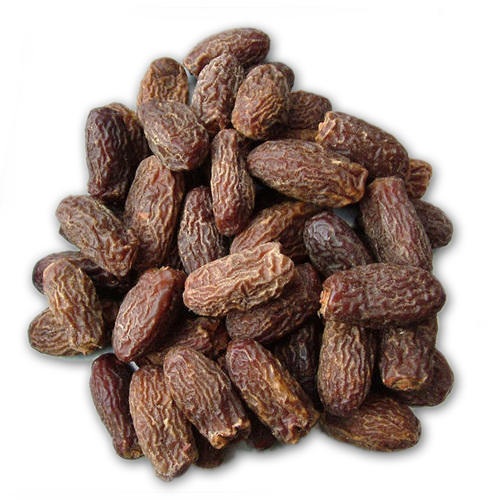 Pile of dark brown wrinkled dried dates, loose fruit