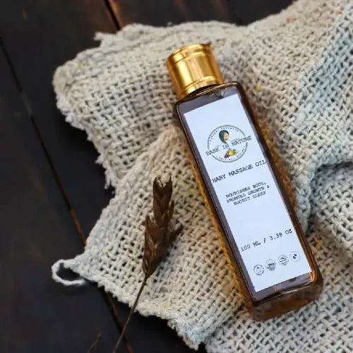 Baby massage oil bottle with gold cap on light fabric cloth