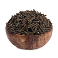 Dried dark peppercorns in a wooden bowl, whole pipali-style grains