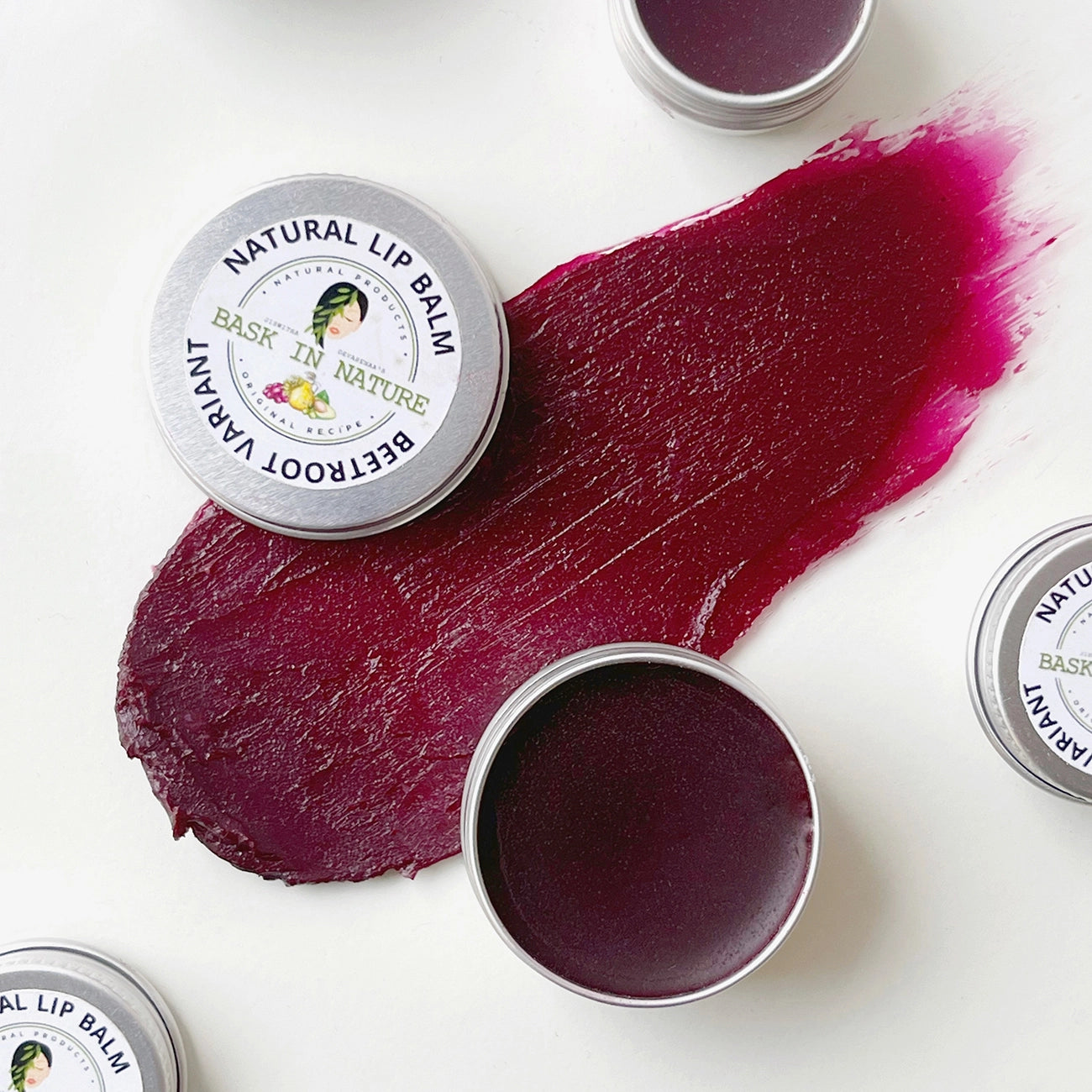 Natural lip balm tin with beetroot-colored balm swatch, round metal container.