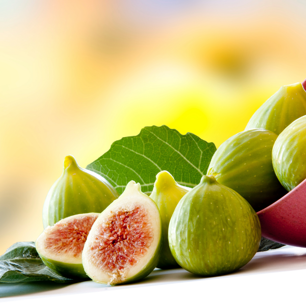 Fresh green figs with one halved, showing pinkish-red interior