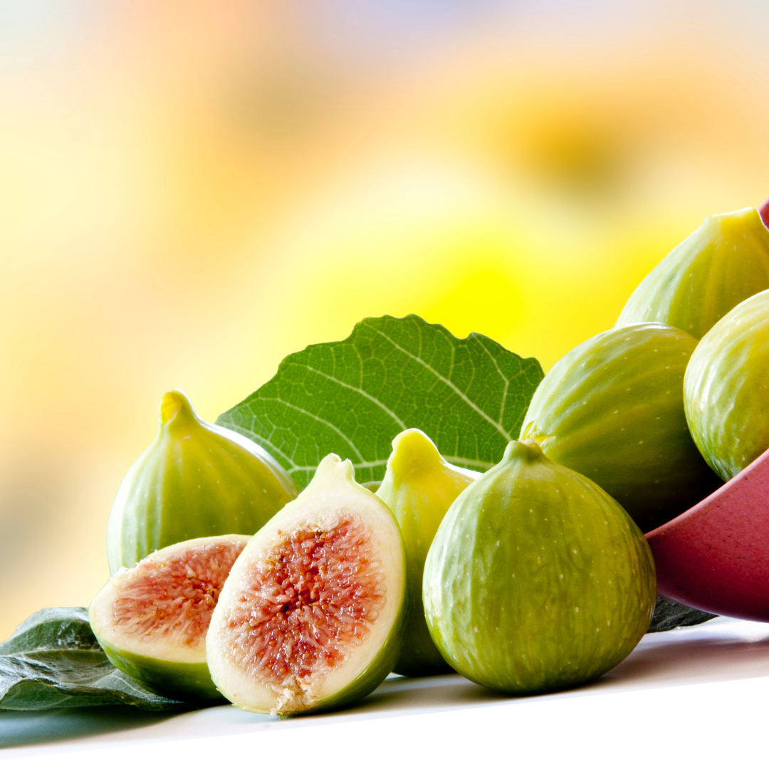 Fresh green figs with one halved, showing pinkish-red interior