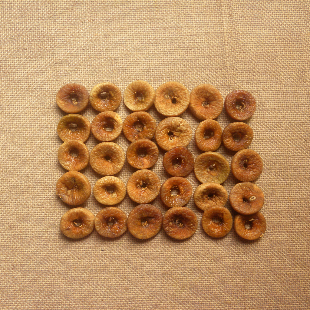 Dried fig slices, round golden-brown pieces arranged on textured fabric