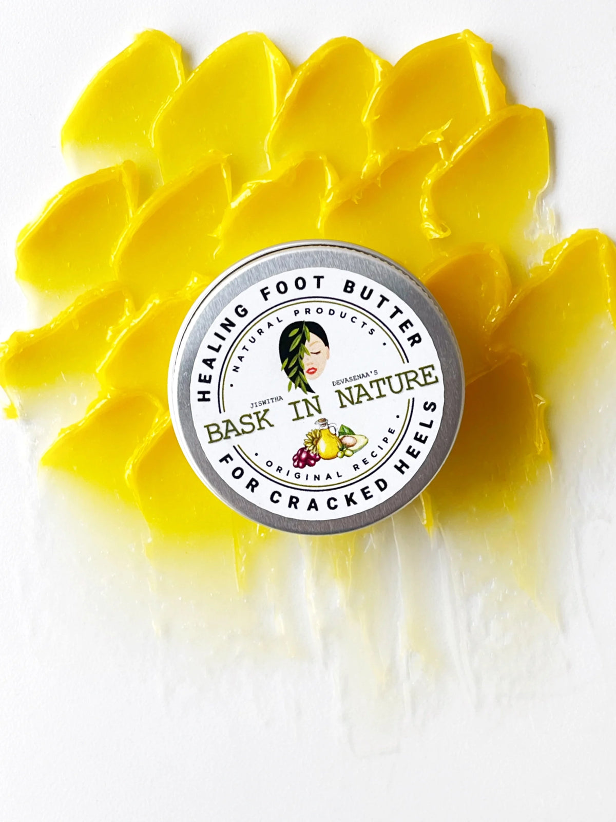 Yellow healing foot butter swirl with Bask in Nature label lid on white.