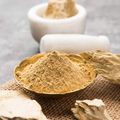 Multani mitti powder in a small bowl, light brown loose powder granules
