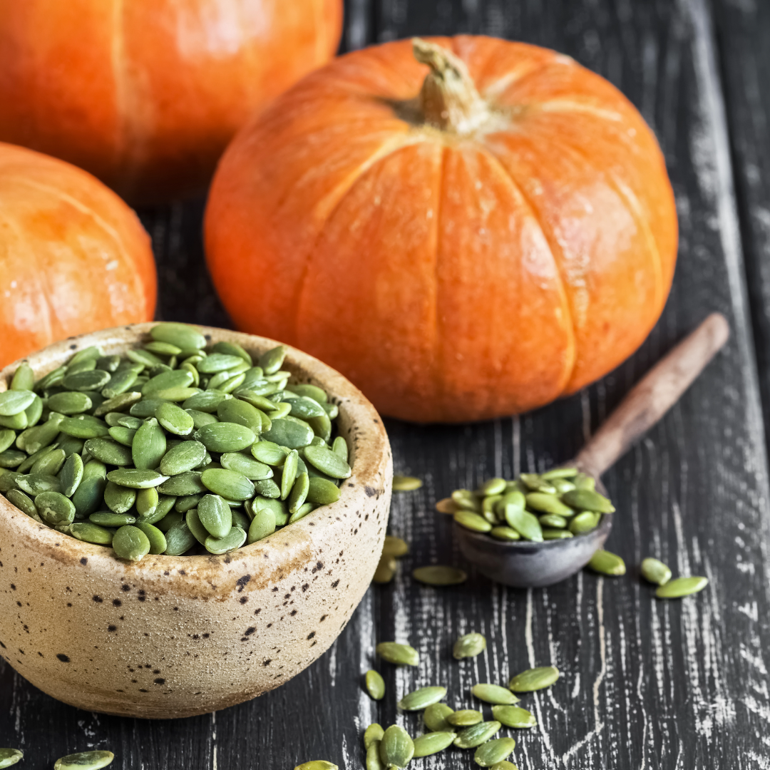 Green pumpkin seeds in speckled ceramic bowl with loose kernels