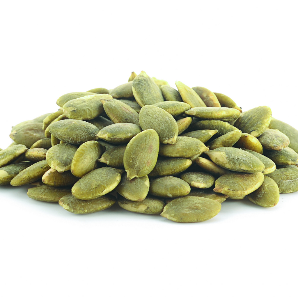 Raw green pumpkin seed kernels piled on a white background