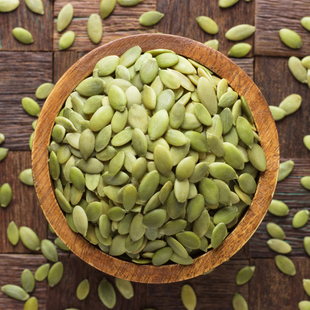 Raw green pumpkin seeds in a wooden bowl, natural kernels