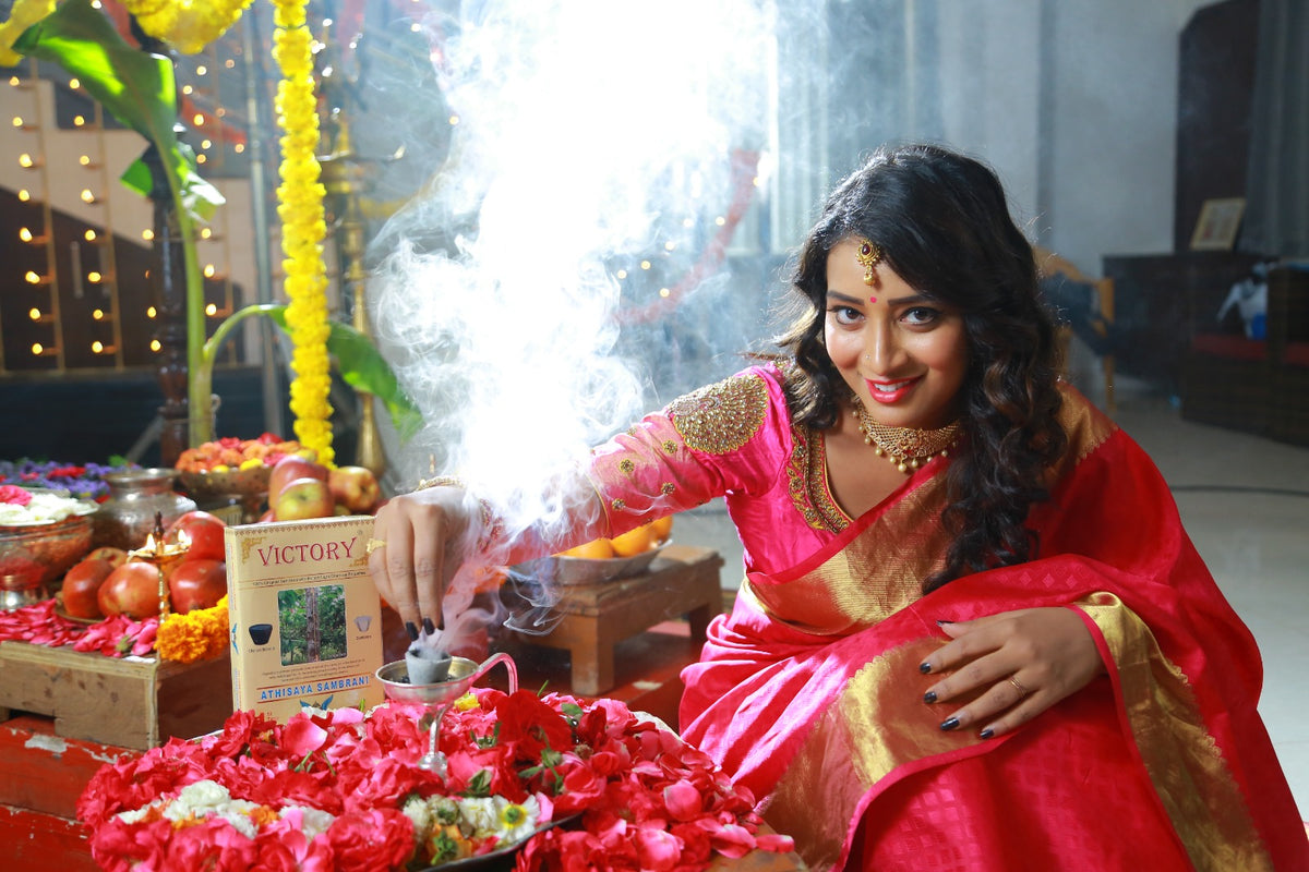 Woman performing incense with smoke, beside Victory incense cup package and flowers