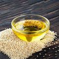 White sesame oil in a glass bowl with golden oil and sesame seeds
