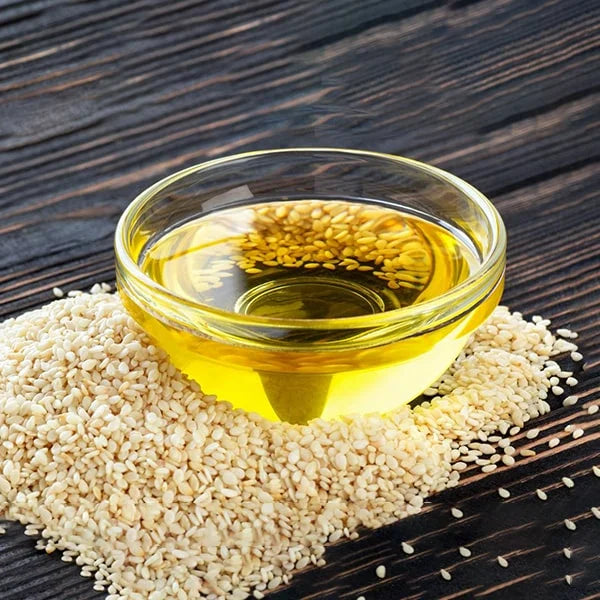White sesame oil in a glass bowl with golden oil and sesame seeds