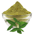 Bhringraj powder in glass bowl with fresh green leaves