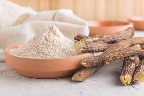 Licorice root powder in terracotta bowl with sliced licorice root pieces