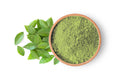 Green henna powder in wooden bowl with fresh leaves