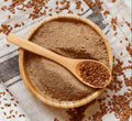 Ground flax seeds powder in wooden bowl with wooden spoon, light brown