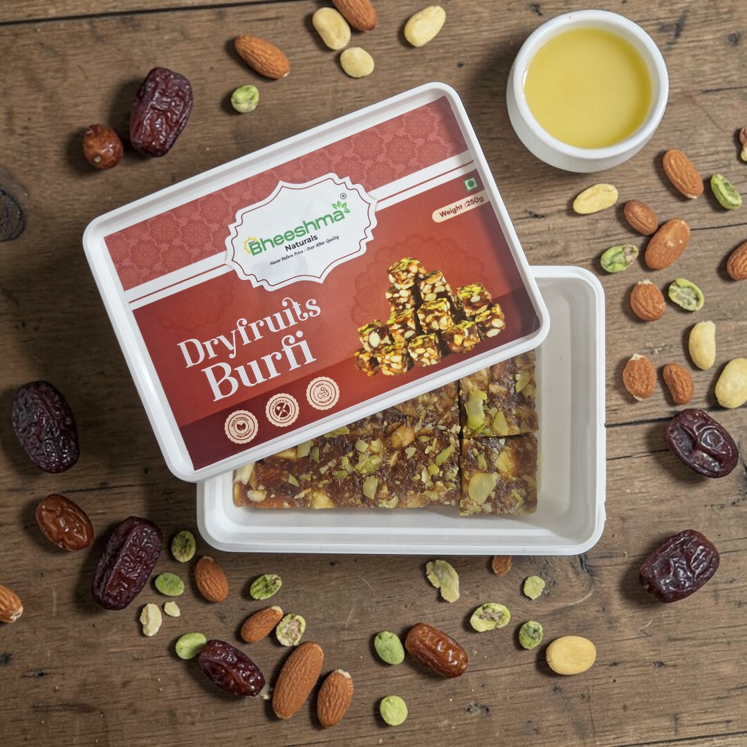 Dry fruits burfi in open tray with chopped nuts scattered, small bowl beside it.