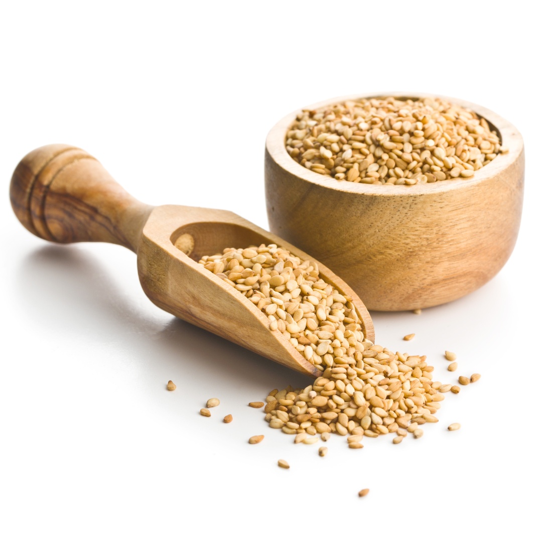 White sesame seeds in wooden bowls and scoop, with loose seeds on table.